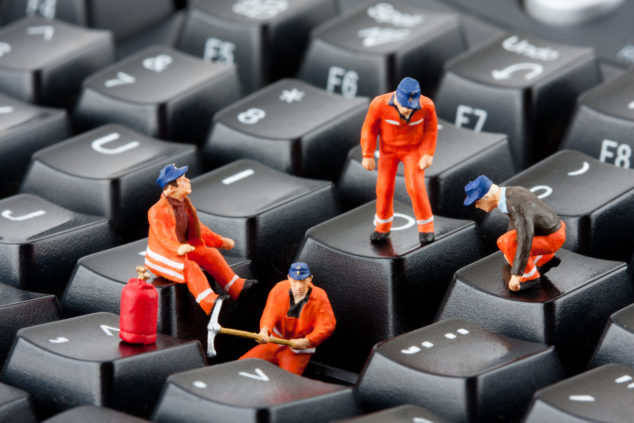 Small figurines of workers repairing computer keyboard